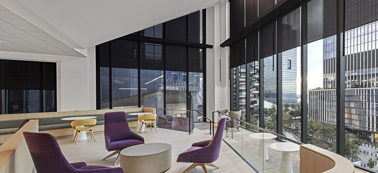 An employee collaboration area with double height automated window shades by Lutron at BlackRock New York