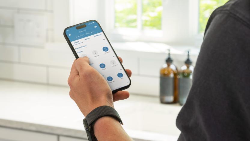Over-the-shoulder view of a person programming kitchen lighting using a Lutron app.