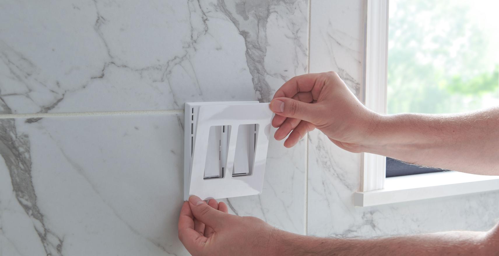 A close up of someone installing a wall plate on a dual switch.