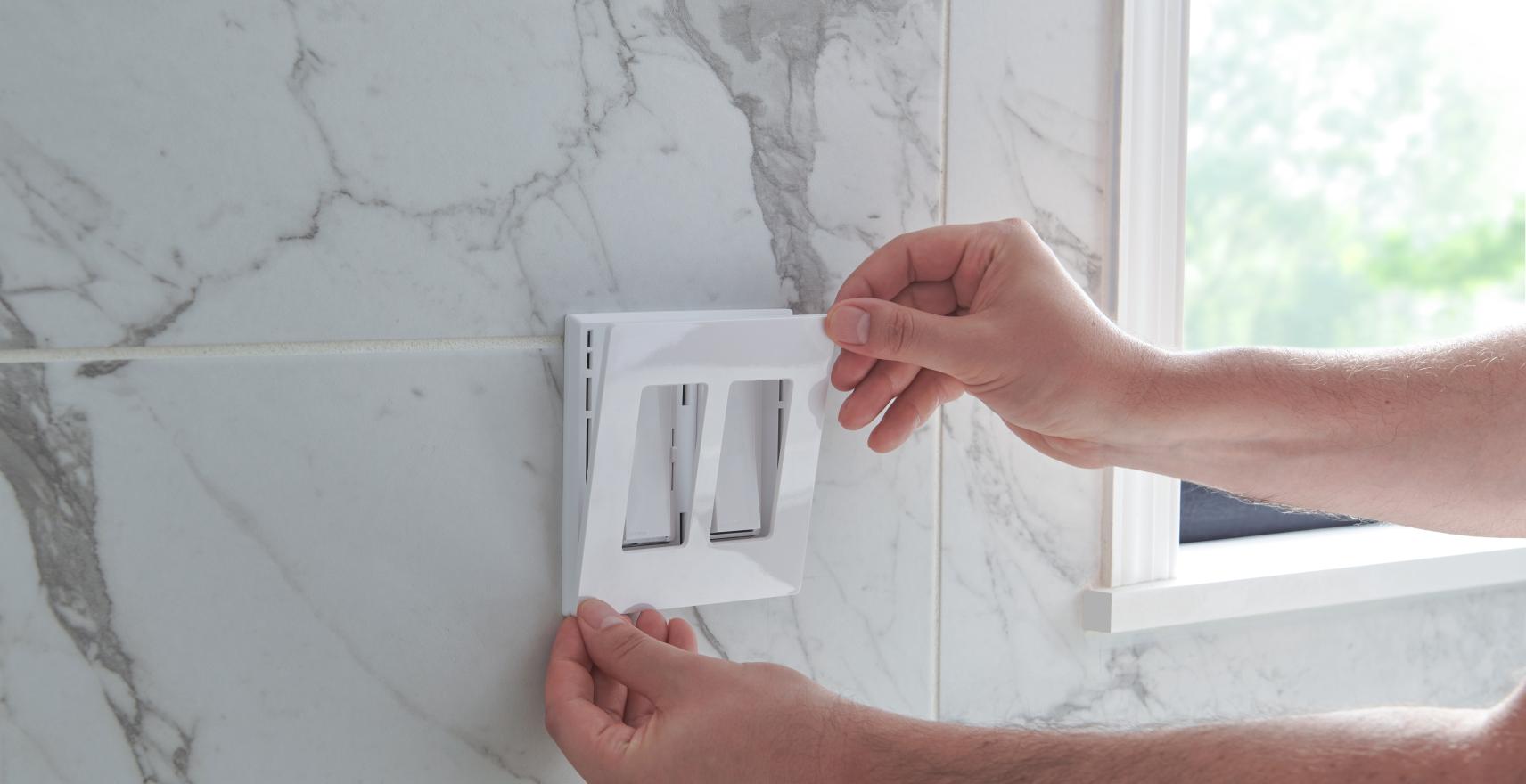 A contractor installing a wallplate on a dual dimmer switch.