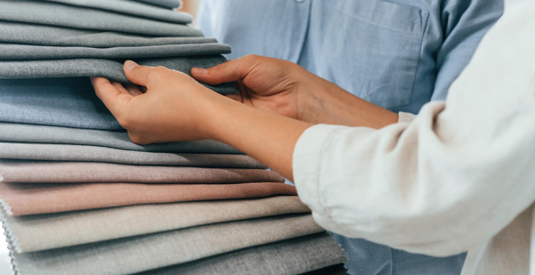 Hands selecting Lutron Roman Shades custom fabric samples for personalized design