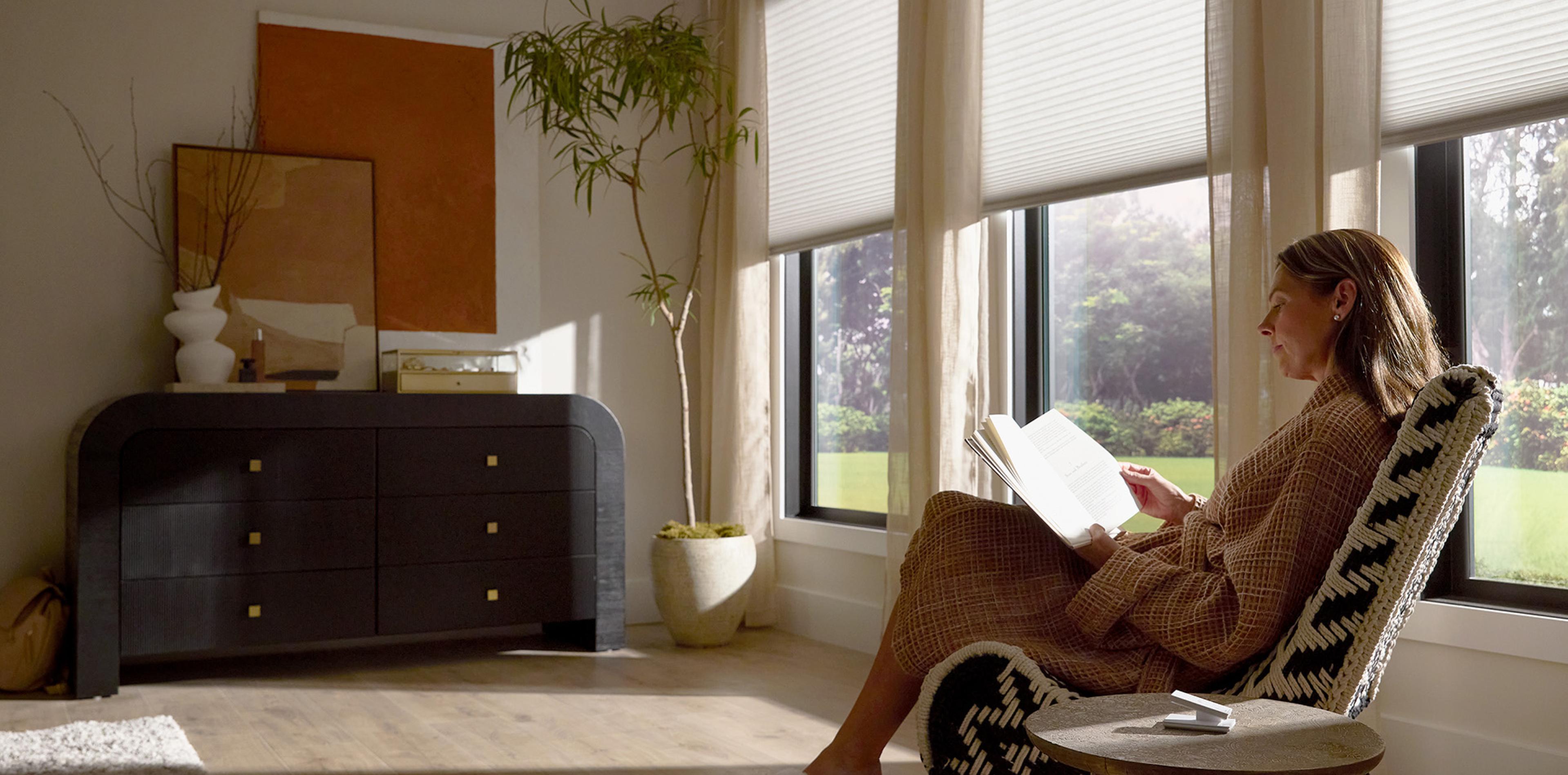 Woman reading in living room with cellular shades honeycomb window treatments