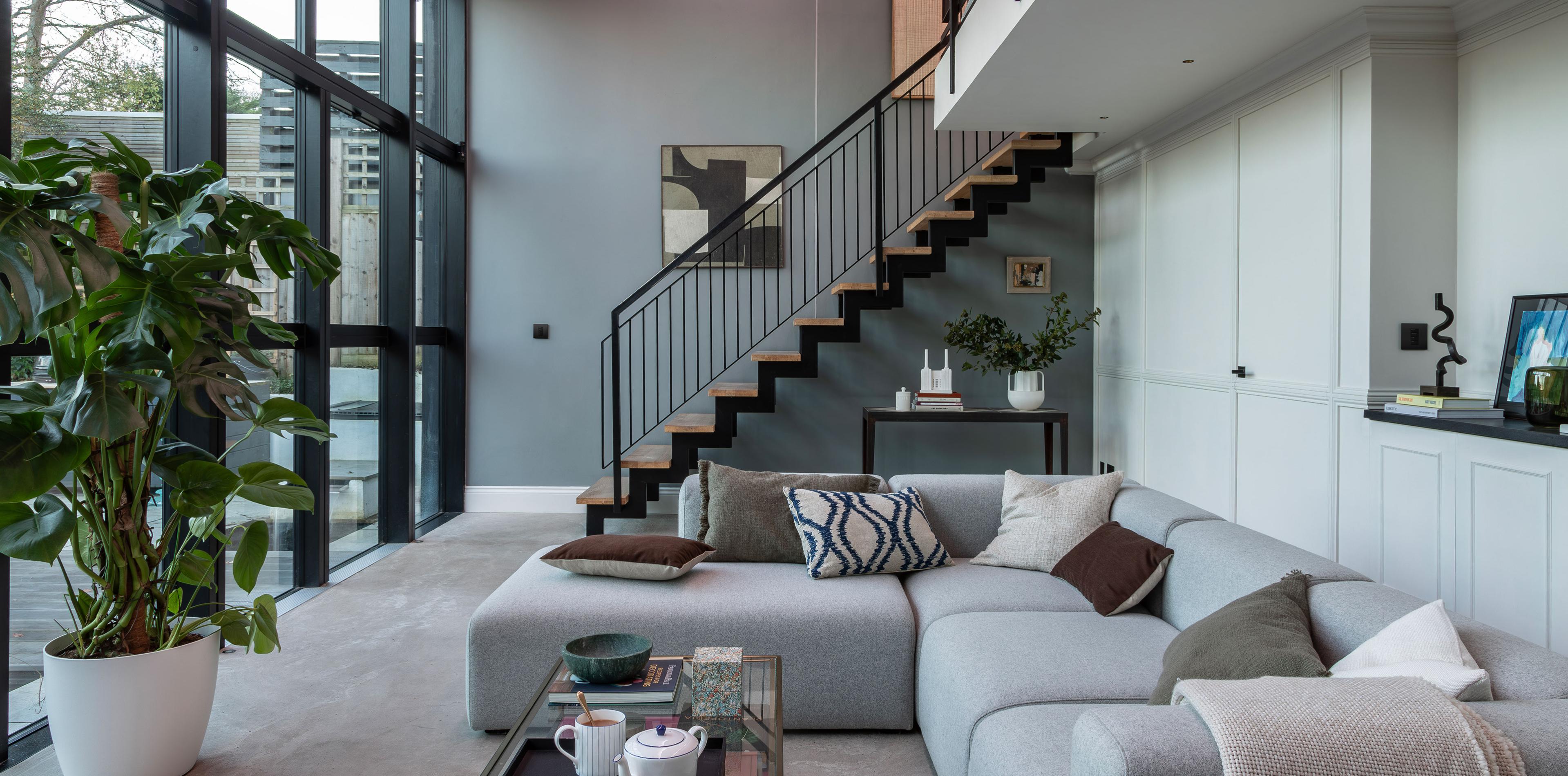 Day-lit living room with ascending staircase in the background.
