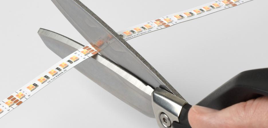 Pair of scissors cutting Rania tape light to a customized size.