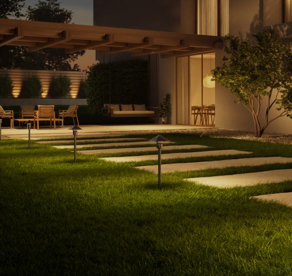 Modern home exterior at dusk with illuminated Lutron x Coastal Source outdoor lighting along a landscaped pathway.