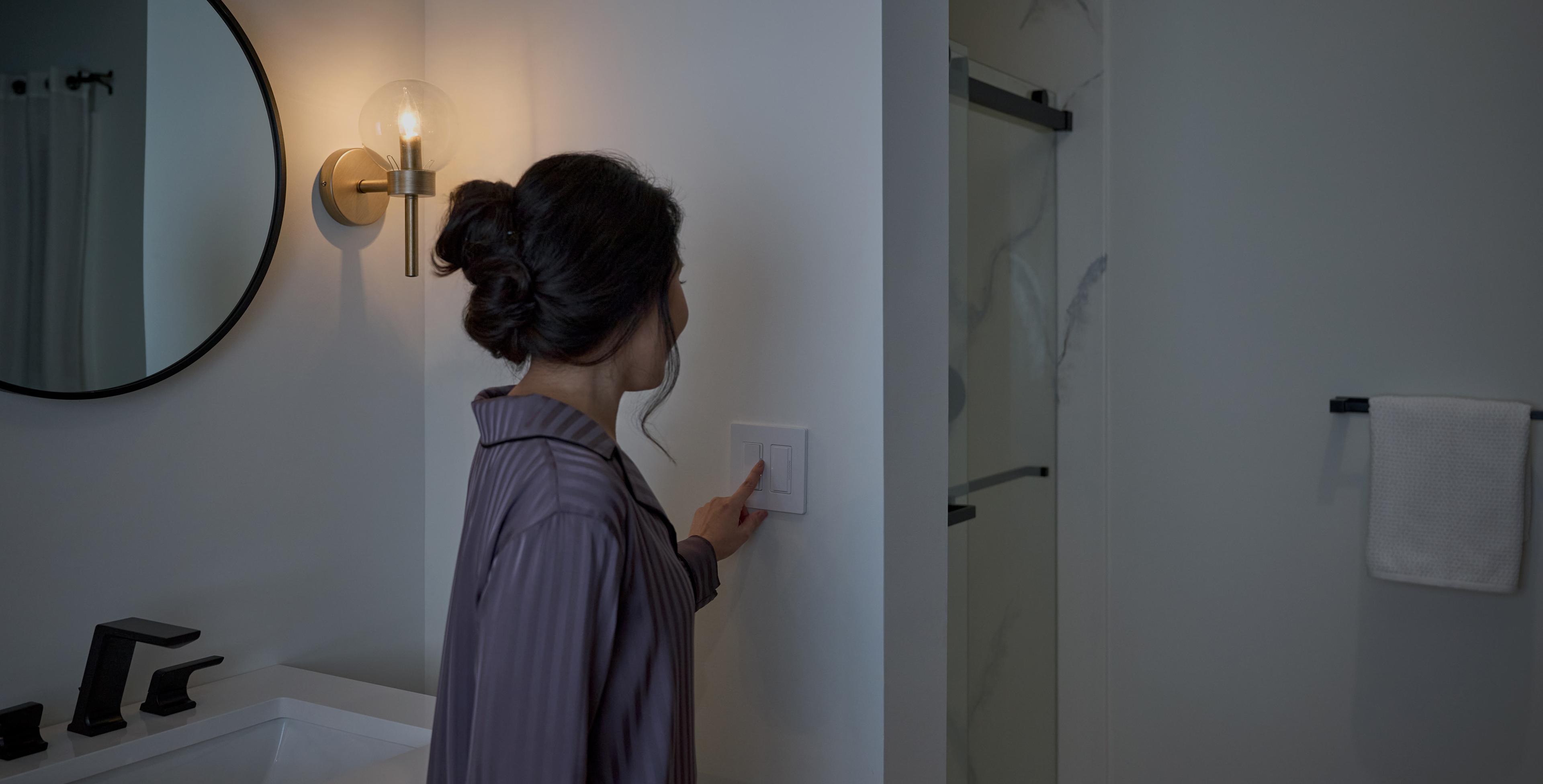 A woman is setting a timer on the switch in her bathroom.