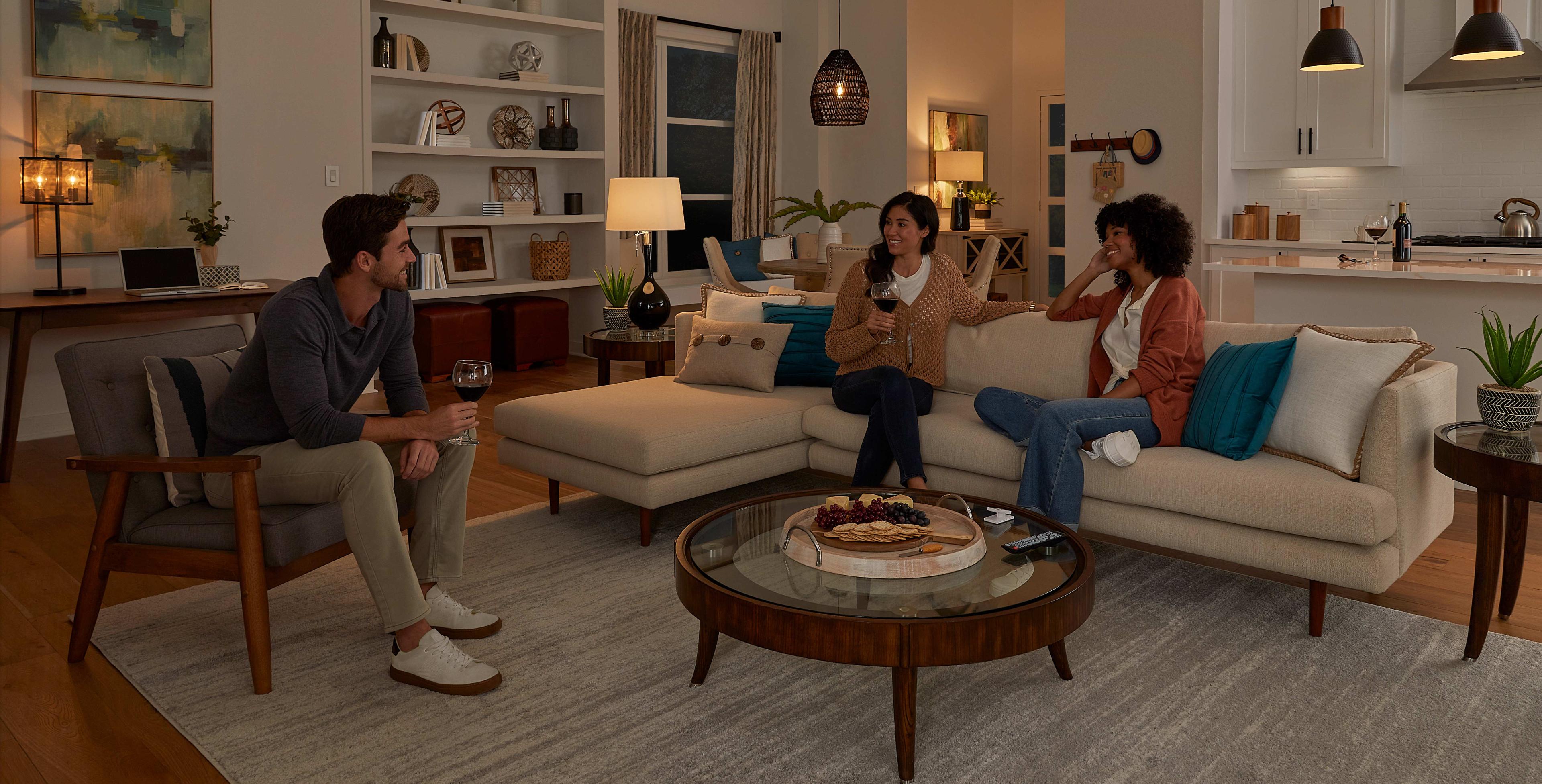 A group of friends hang out in a living room in a soft, ambient glow.