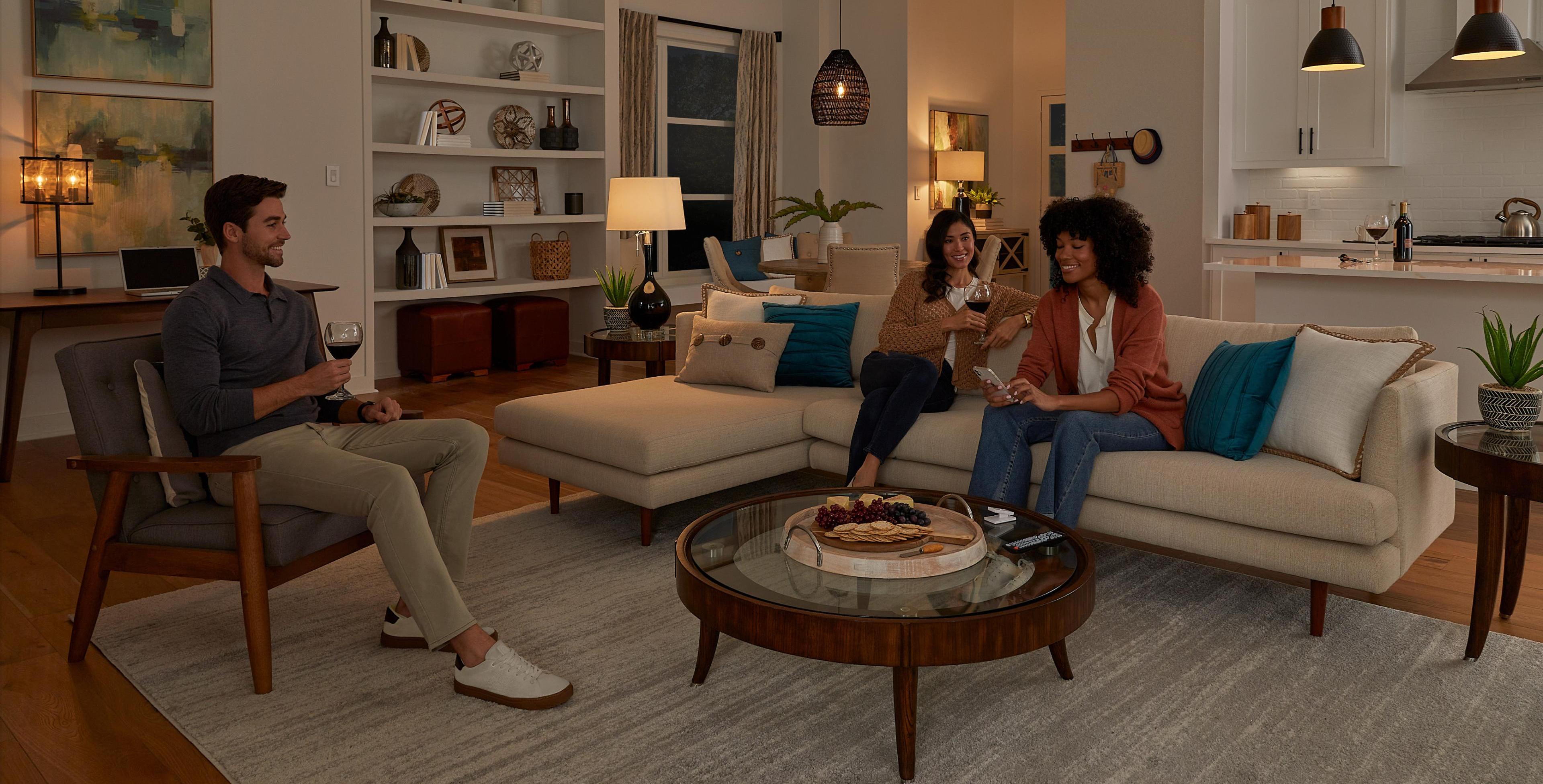 Three friends hanging out in a living room with the lights dimmed to a warm ambiance.
