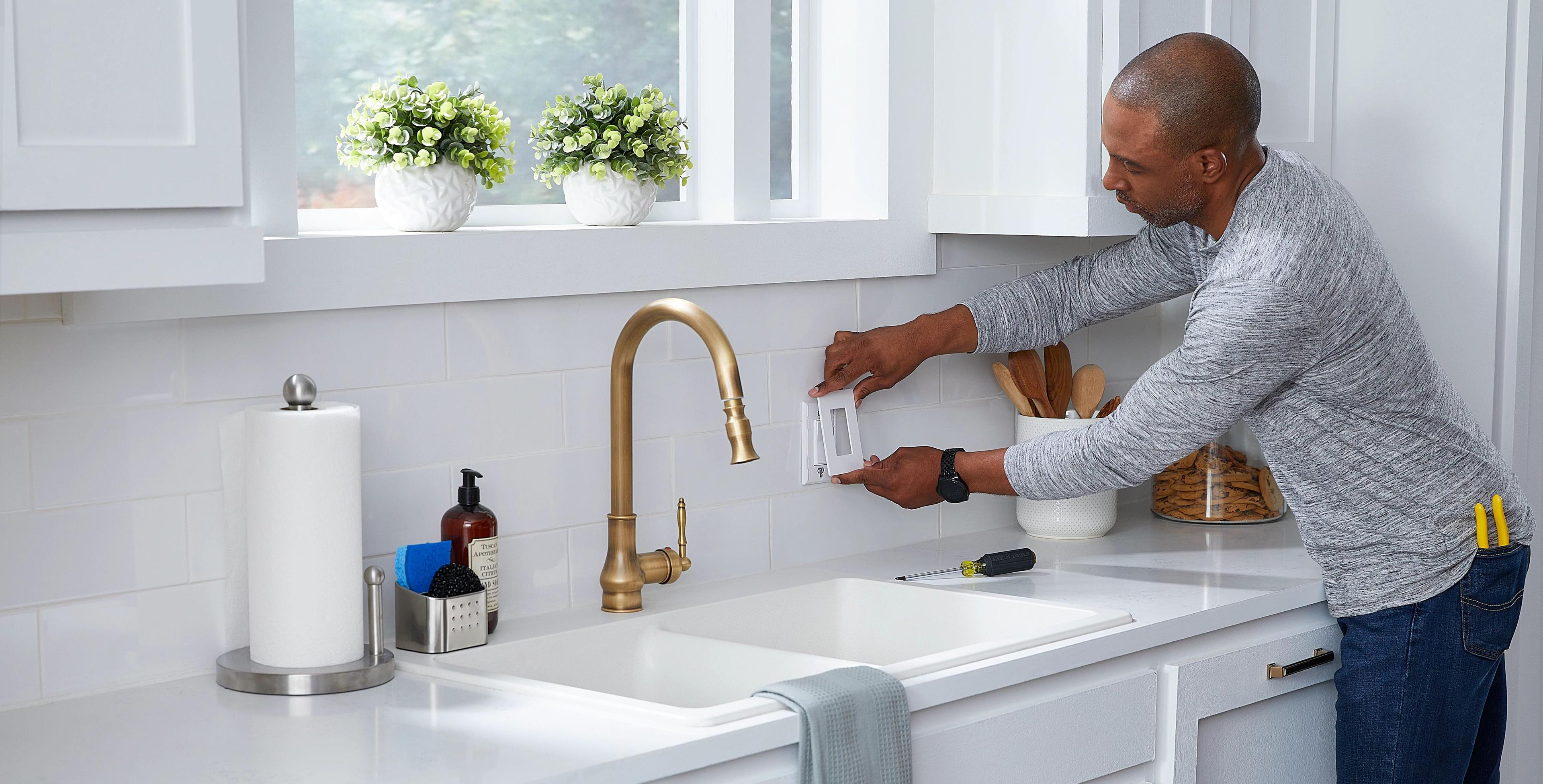 Homeowner installing Sunnata dimmer switch in modern kitchen with white countertops