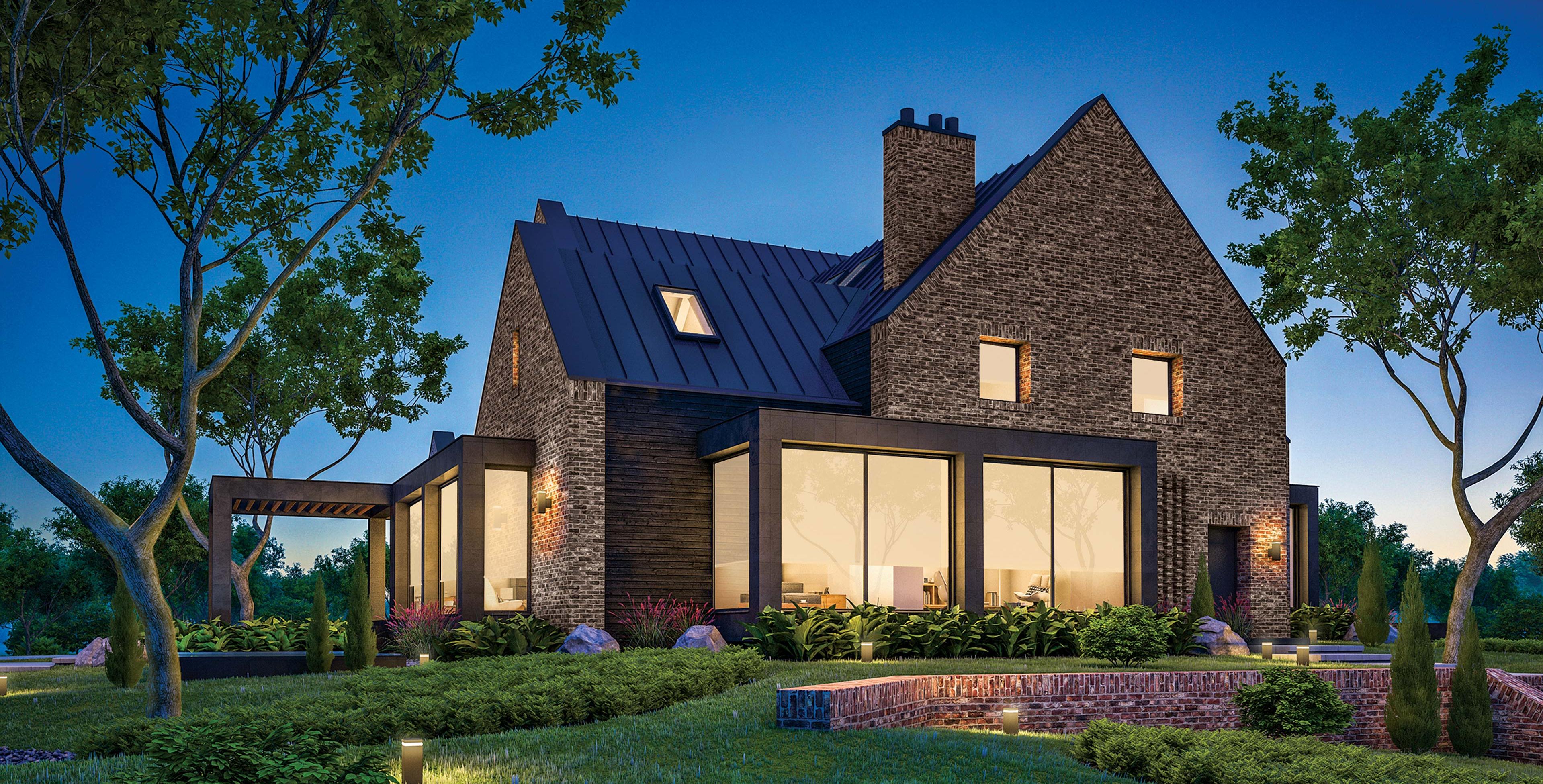 Grey-brick home at dusk with interior lights on.