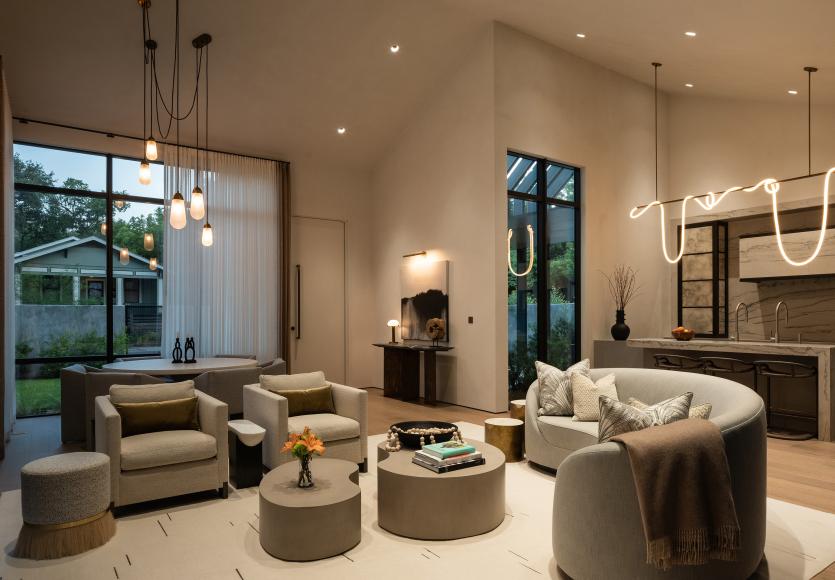 Living room with large windows and neutral furnishings shown in bright daylight.