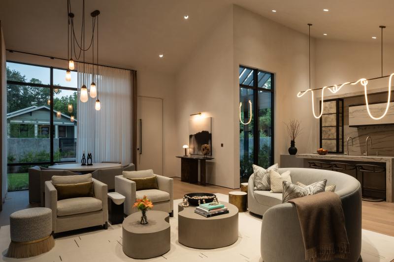 Living room with large windows and neutral furnishings shown in bright daylight.