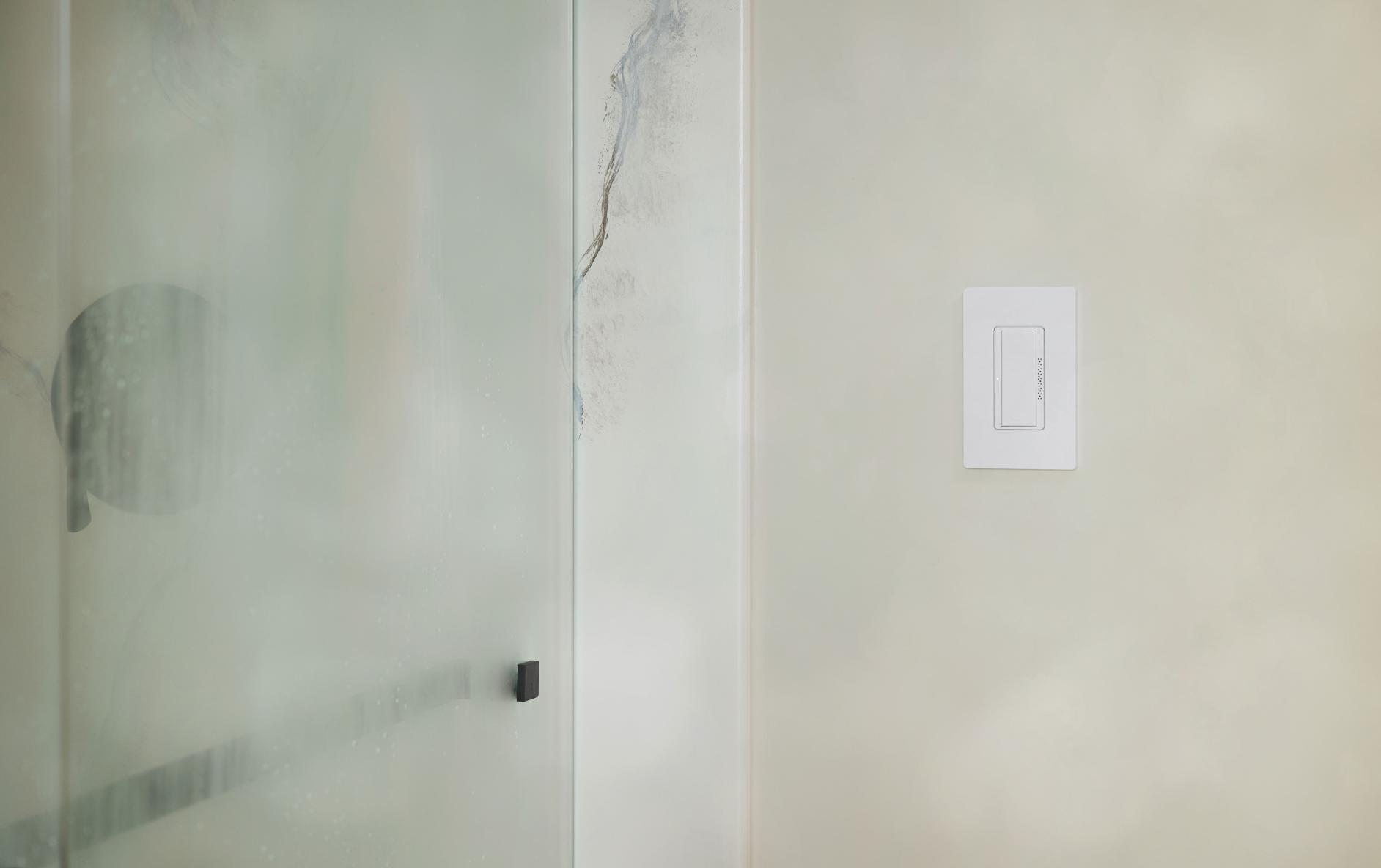 A steamy shower door with the humidity switch on the nearby bathroom wall.