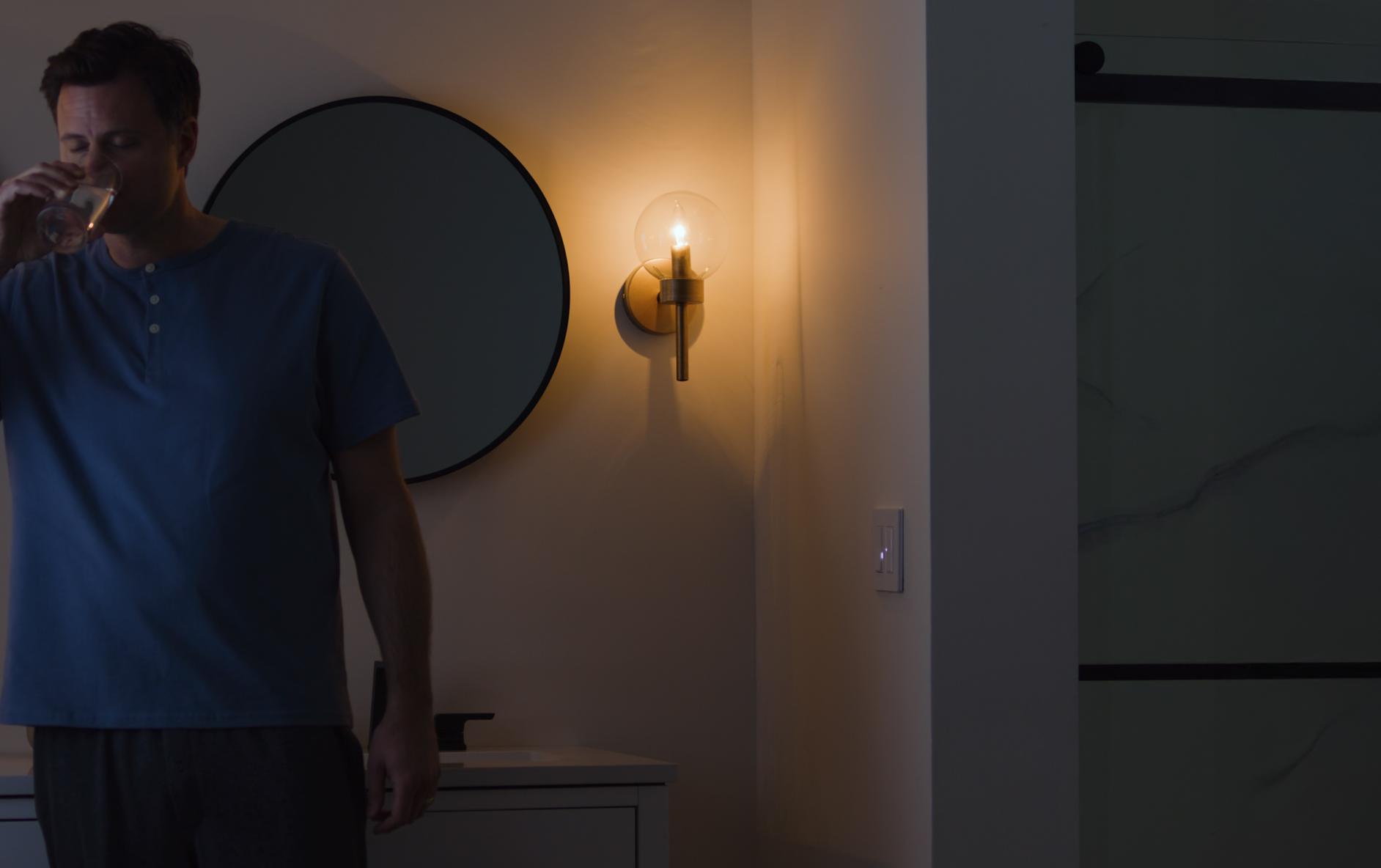 The Diva dimmer with Night Mode casts a low light while a man gets a drink at night.