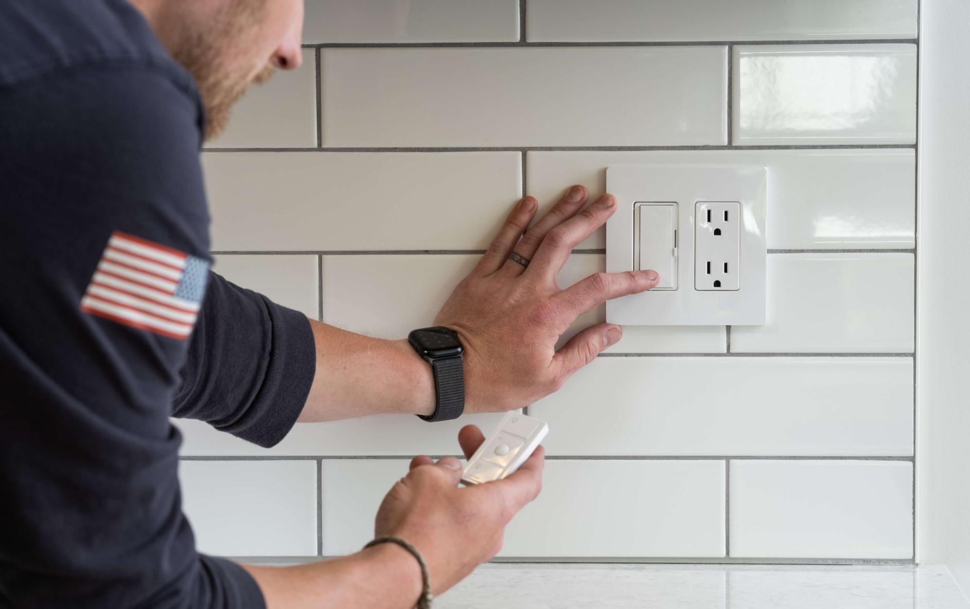 Person installing a Lutron light switch with a Pico remote on a tiled kitchen backsplash