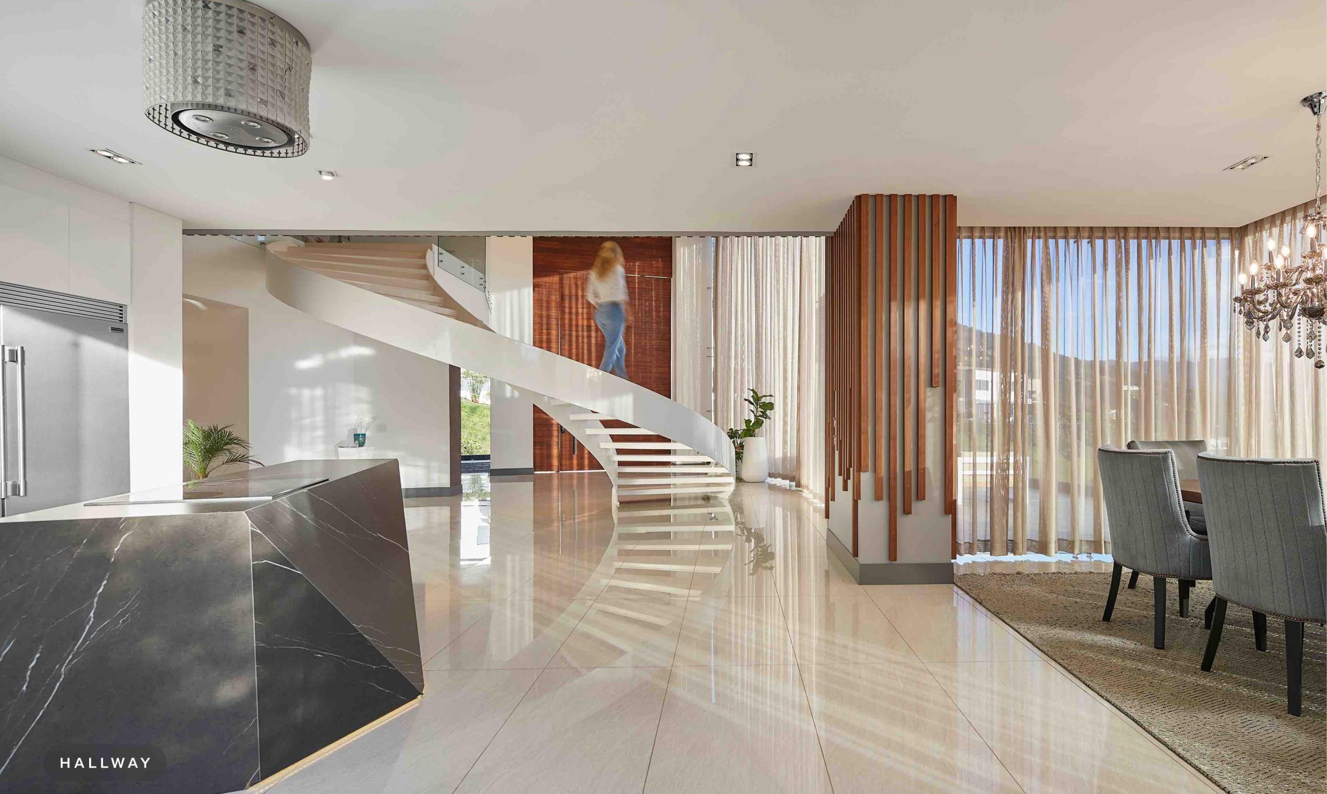 Hallway with a curved staircase beside floor-to-ceiling sheer drapery and a dining area.