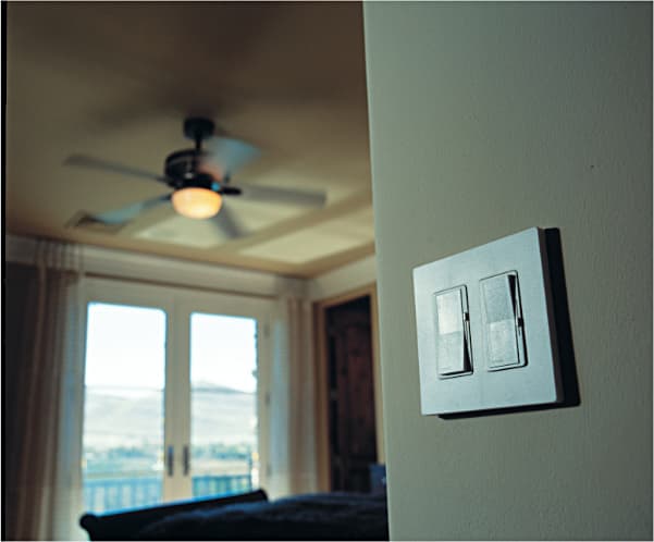 Dimmer switches on the wall with a fan light in the background